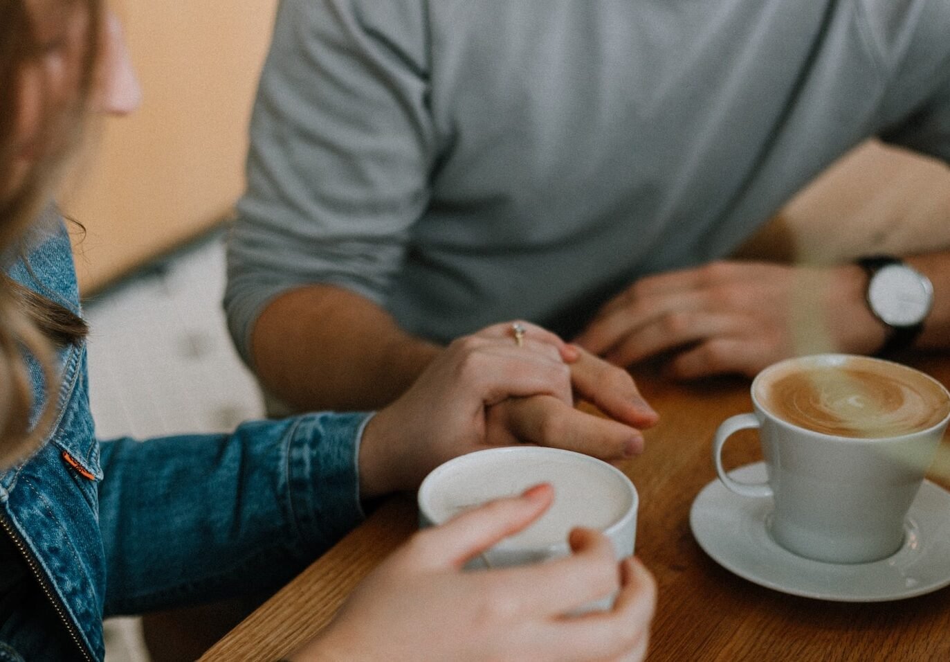 Man and woman having a coffee holding hands for support